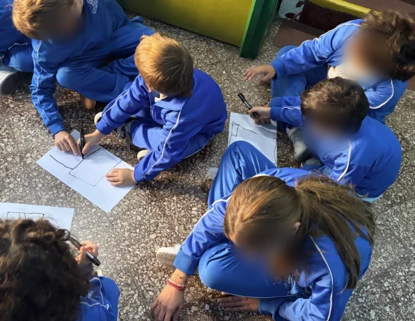 Estudiantes de 6.º grado dibujando sentados en el piso del patio