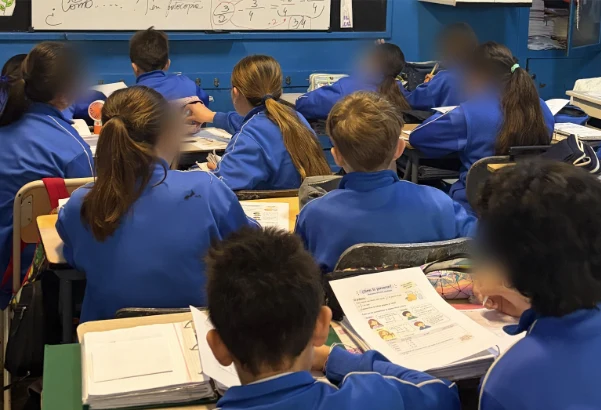Estudiantes de 6.º grado trabajando en sus bancos dentro del aula
